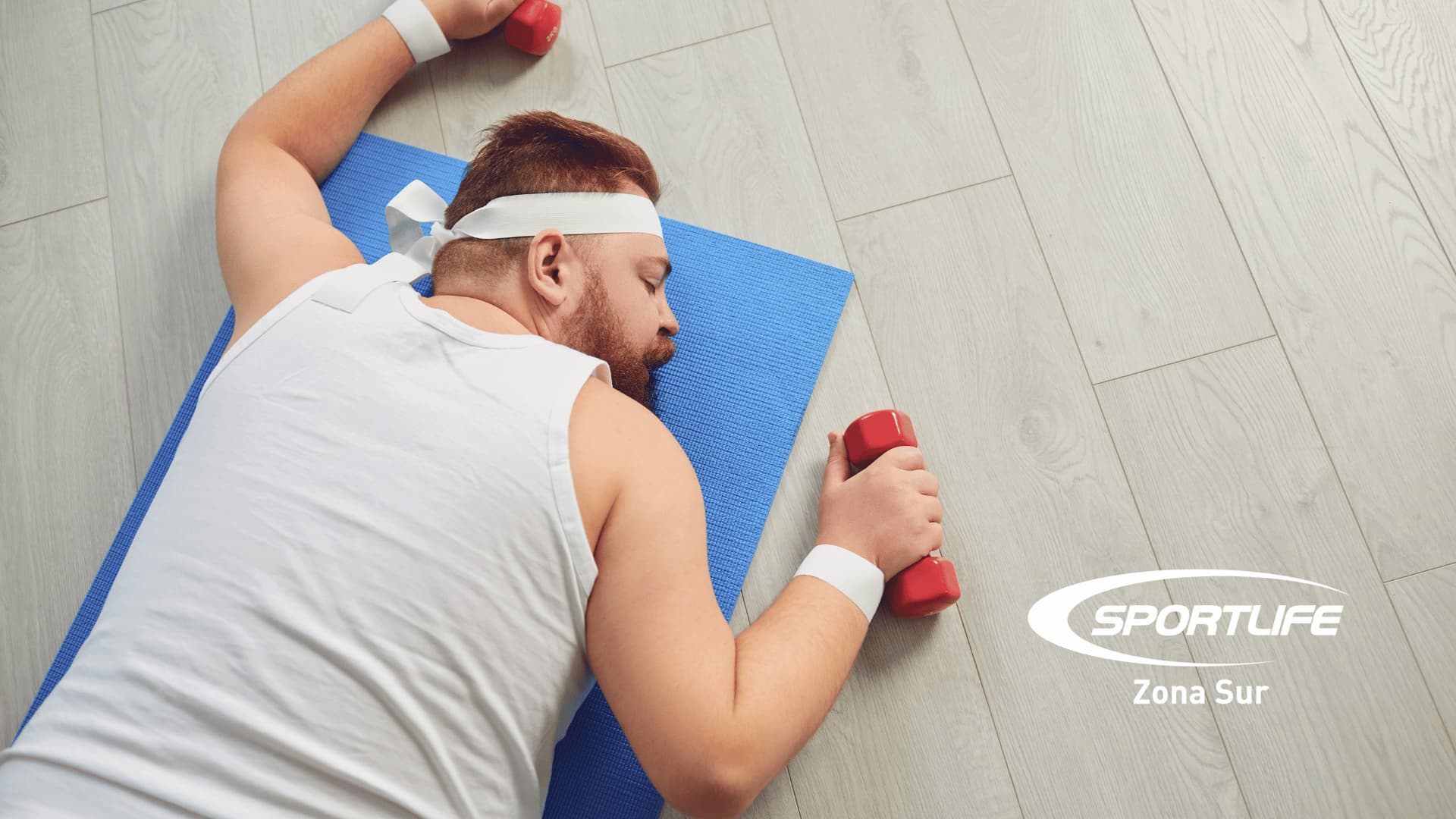 Hombre con sobrepeso en colchoneta sosteniendo mancuerna, mostrando el logo de Sportlife Zona Sur, reflejando el desafío de iniciar una rutina de entrenamiento.